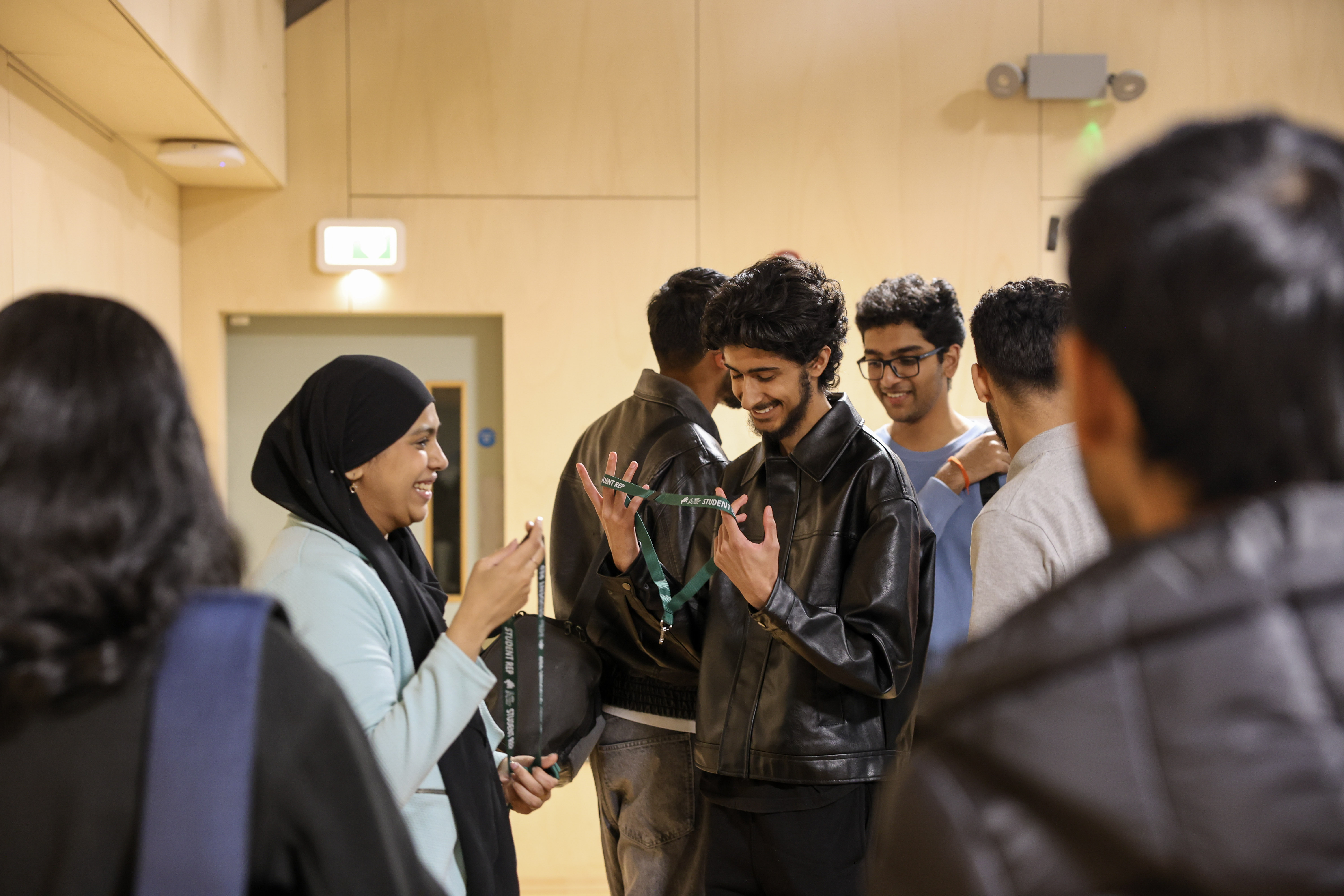 Students smiling together holding student rep lanyard